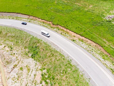 Top view of the road serpentine in the mountains, on the road cars