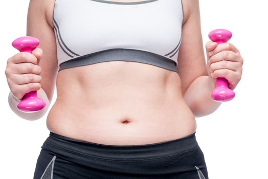 weight loss, belly close up and in the hands of a dumbbell