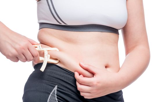 fat woman measures the level of fat on the abdomen tool