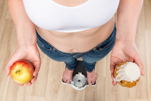 concept of choice and weight loss, a woman on scales with an apple and a donut