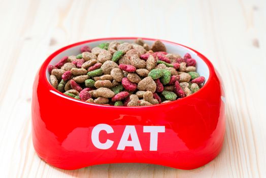 bowl for the cat on the floor is filled with dry food, close-up photo