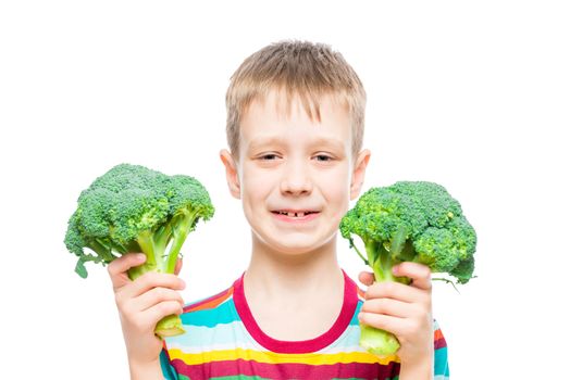 portrait of a boy with broccoli in hands on white background in studio