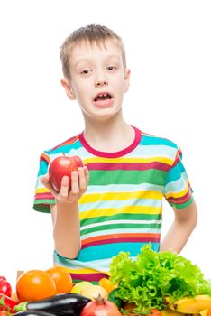 Vertical portrait of a boy with a red ripe apple in the studio on white background isolated