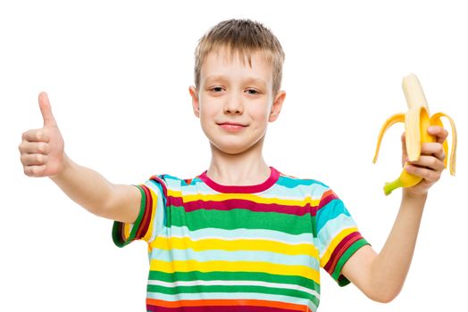 Portrait of a happy boy on a white background with a banana in his hand isolated
