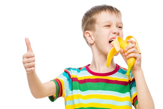 Happy boy eats tasty banana on white background, portrait is isolated