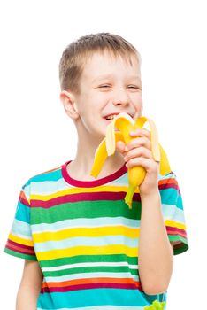 vertical portrait of a boy who eats a tasty banana on a white background, portrait is isolated