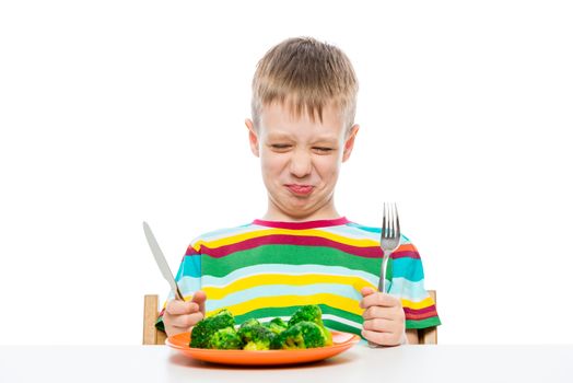 Grimace of a boy who does not like broccoli, portrait on a white background