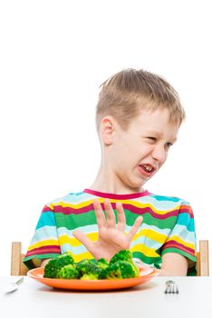 10-year-old boy refuses a plate of broccoli for lunch, concept photo kids and food