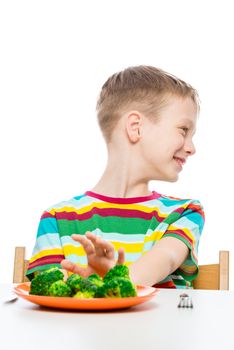 boy moves back plate with tasteless broccoli, portrait on white background isolated