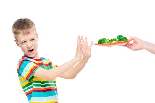 Boy refuses plate of broccoli for lunch, portrait is isolated on white background