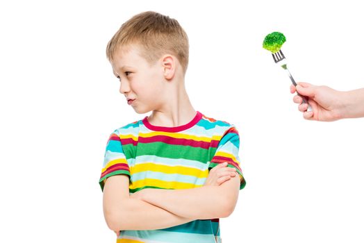 Offended displeased boy refuses serving of healthy broccoli, portrait is isolated