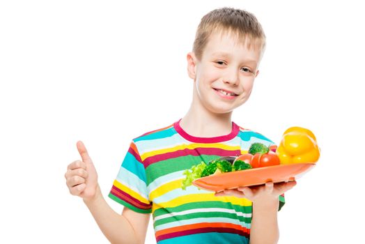satisfied boy with a plate of healthy vegetables isolated on white background portrait