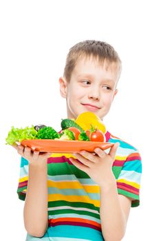 vertical portrait of a boy with a plate of vegetables on white background isolated
