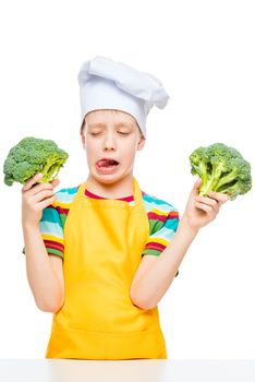 vertical portrait of a boy who does not like broccoli in a cook's cap on a white background