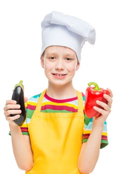 vertical portrait of a child in a cook hat with pepper and eggplant on a white background