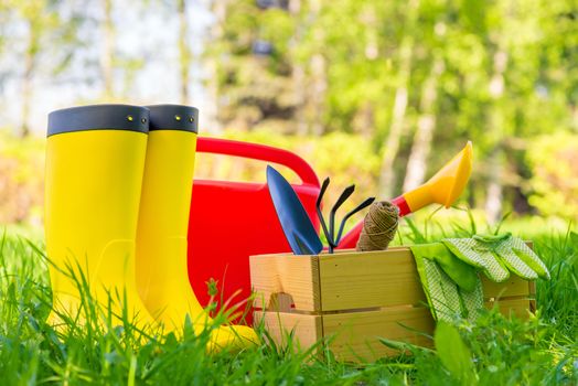 garden tools, watering can and gardener's boots close-up in the backyard of the house