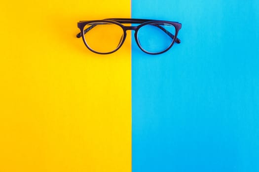 stylish glasses on a bright blue-cyan and yellow-orange background, top view, isolated. Copy space. Flat lay.
