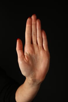 Woman hand palm showing stop gesture over black background, side view