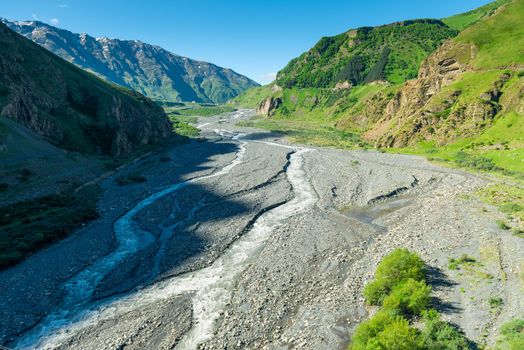 Stormy mountain river against the backdrop of high green Caucasus Mountains in Georgia