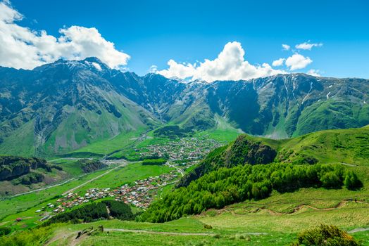View of the mountain peaks of the Caucasus and the village of Gergeti in the valley, Georgia in summer