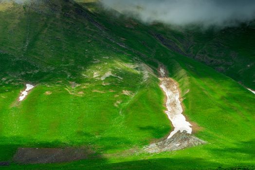 Green mountainside with remnants of snow after winter, Caucasus in June