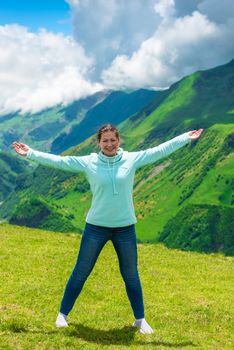 Woman in the mountains with arms spread to the sides with happy emotions