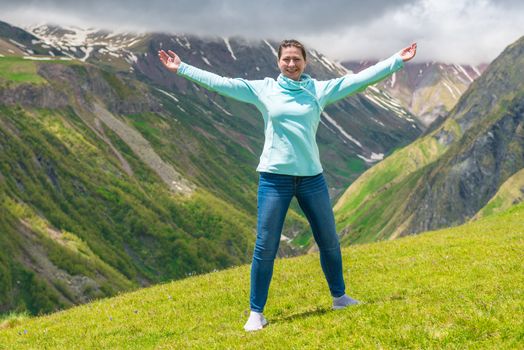 Portrait of a beautiful happy woman with arms outstretched in the mountains
