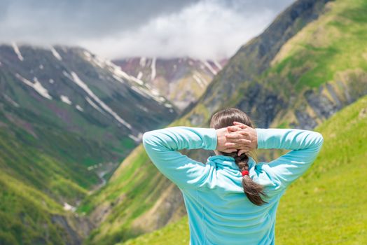 Woman admires beautiful scenery in the mountains, view from the back