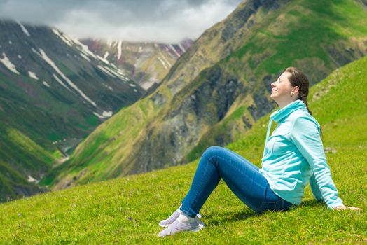 Happy woman resting and admiring the mountains in the campaign to the Caucasus