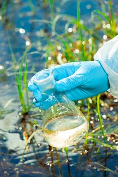 environmentalist hand with a flask produces a set of water for research from the lake