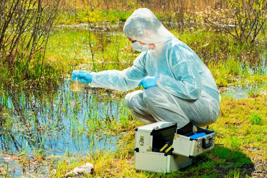 environmentalist on the shore of a forest lake takes water samples after an environmental disaster