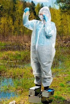 ecologist and his equipment for the study of the composition of water in the lake, a portrait in nature during work