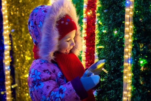 The girl watches Christmas fires in decoration of the city