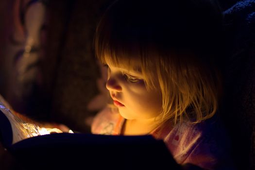 The girl reads the magic book, from the book light on the person, a close up shines
