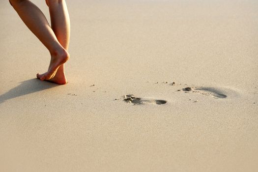 Female feet going on an ocean beach