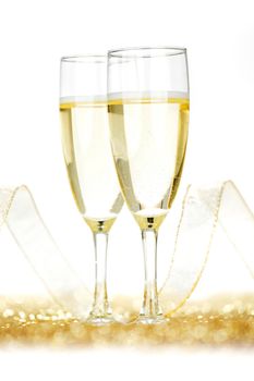 Two champagne glasses and golden shiny glitters isolated on white background