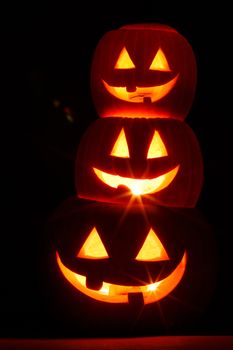 Stack of halloween pumpkin glowing faces on dark background