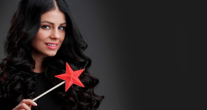Woman with red star shaped magic wand, dark background
