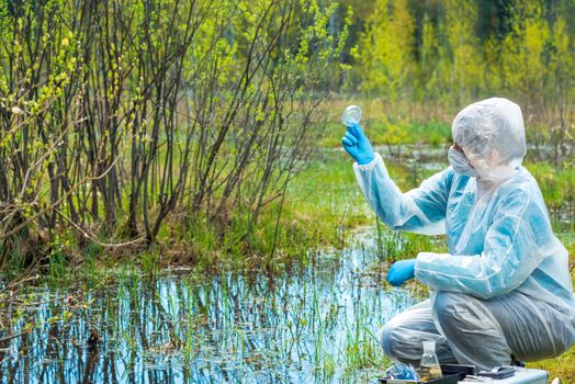 woman studies water and plants from forest lake, chemical composition and bacteria