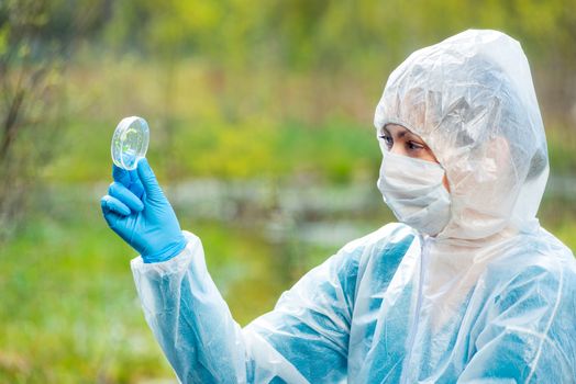 a researcher with a flask and samples of plants from a forest river is studying