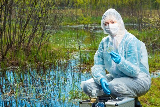 environmentalist chemist with samples of water and plants from the forest river conducts research