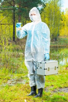 water intake for research in the laboratory, environmentalist in protective clothing at a water source in the forest