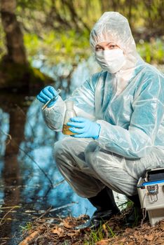 ecologist and with test tubes and flasks analyzes water in a forest pond