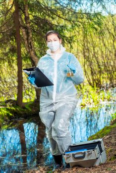 environmentalist biologist in the forest takes water samples in the flask