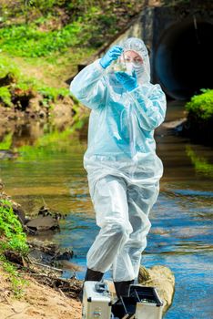 dangerous sewer water, a scientist takes a sample of water in protective clothing