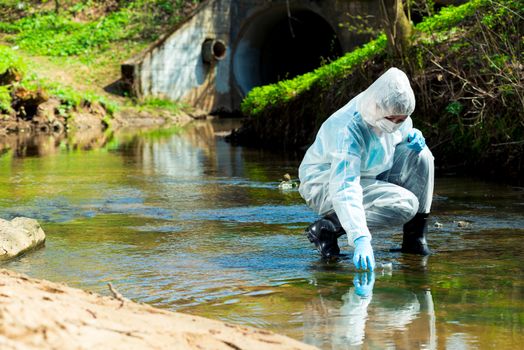 ecological disaster, contaminated water comes out of the sewage system - an ecologist takes a sample of water for research
