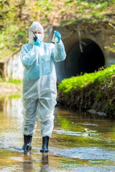 concept ecological disaster, environmental scientist with an infected sample of water from the sewer and walkie-talkie