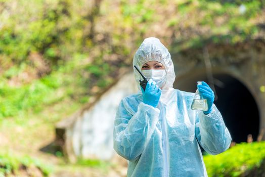 portrait of a scientist with a water sample from the sewer and walkie-talkie