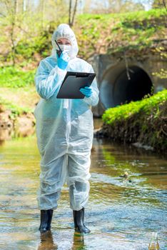 a female scientist with a walkie-talkie and a notebook fixes environmental disasters in the river