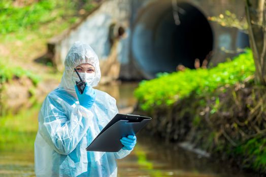 a scientist with a walkie-talkie on the background of a sewer pipe